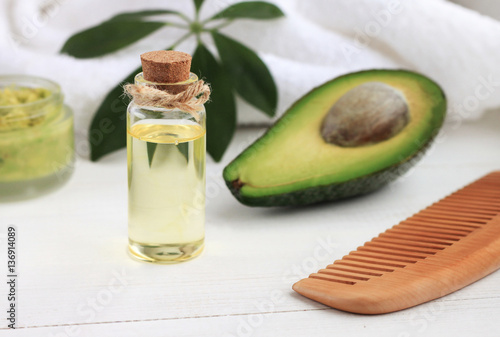 Avocado oil in bottle, green fruit, comb. Cosmetic benefits, healthy hair and skin care.