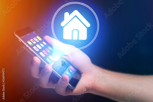 Businessman hand holding mobile phone with home icon