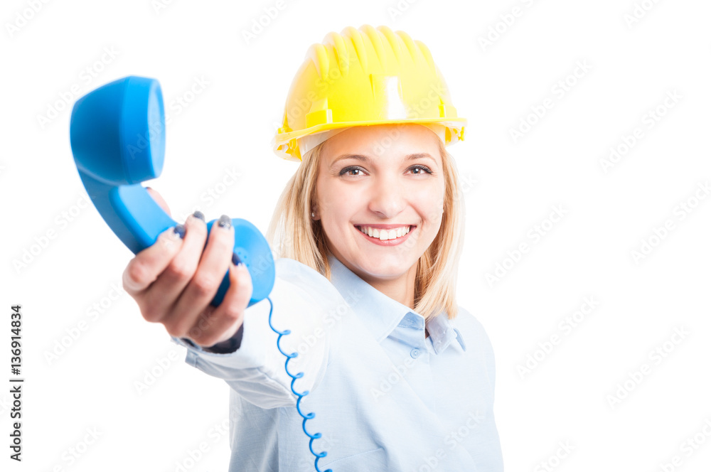 Woman architect wearing helmet showing telephone receiver Woman architect wearing helmet showing telephone receiver