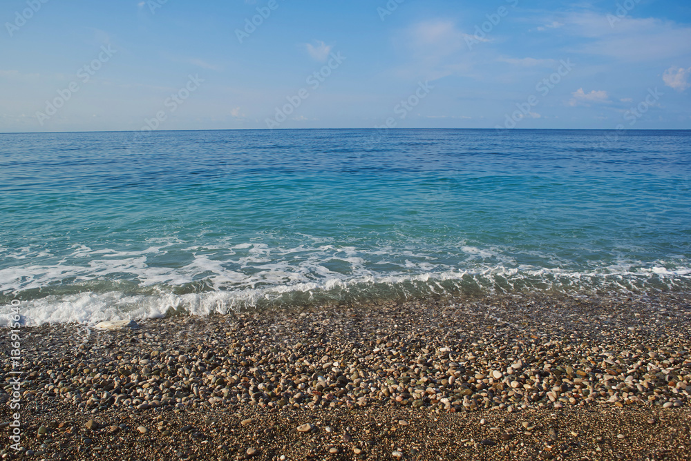 calm blue sea and pebble beach and blue sky