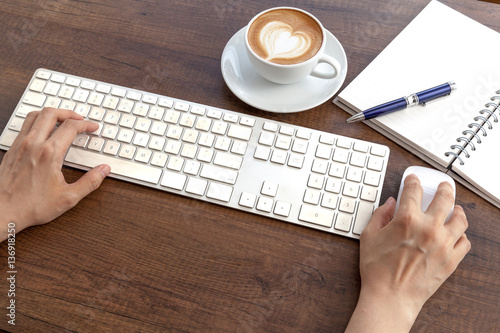 Obraz na płótnie Typing and have a coffee cup of latte art heart shape on wooden w salonie