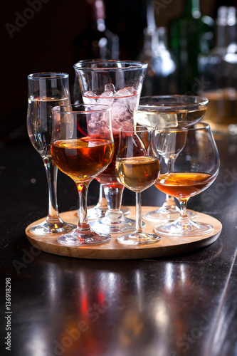 glasses of different shapes with different alcohol on a wooden round board on the bar