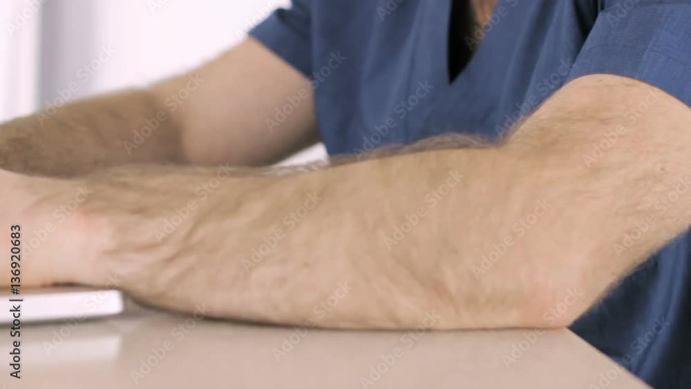 Doctor sitting at a computer, typing text on keyboard Doctor sitting at a computer, typing text on keyboard