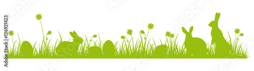 Silhouettes of cute Easter bunnies on a flower meadow 