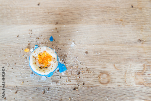 Kaputtes Osterei nach Eierpicken auf einem Holzbrett mit Salz und Pfeffer