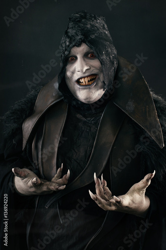 Happy crazy smiling vampire with large scary nails. Undead monst photo