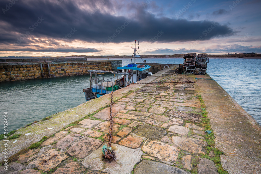 Beadnell Harbour North Pier, at Beadnell village on the Northumberland  coastline, which is a small fishing harbour set into Beadnell Bay. Disused  medieval Lime Kilns sit in the harbour Stock Photo