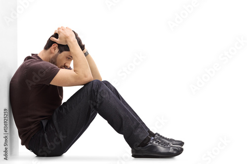 Depressed man sitting on the floor with his head down photo