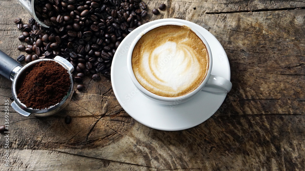 Cappuccino Coffee. A cup of latte, cappuccino or espresso coffee with milk put on a wood table with dark roasting coffee beans. Drawing the foam milk on top. Cappuccino Coffee. A cup of latte, cappuccino or espresso coffee with milk put on a wood table with dark roasting coffee beans. Drawing the foam milk on top.