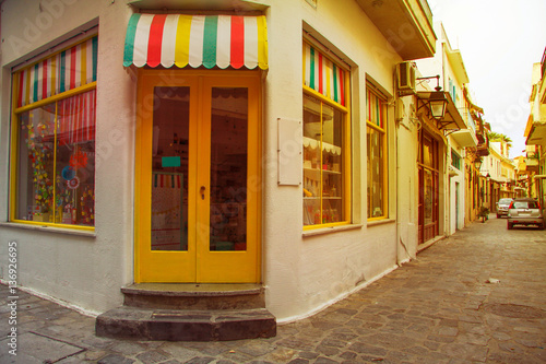 Traditional multicolor facade of shop from the street greek island town panorama. Image with sunkissed effect, toned