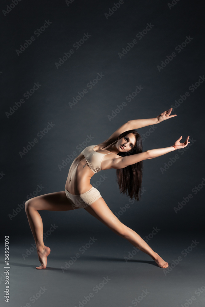 Young slim contemporary dancer posing on a black studio background