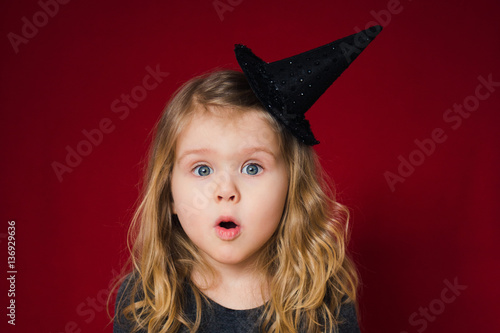смешная девочка в шапке волшебника открыла рот от удивления