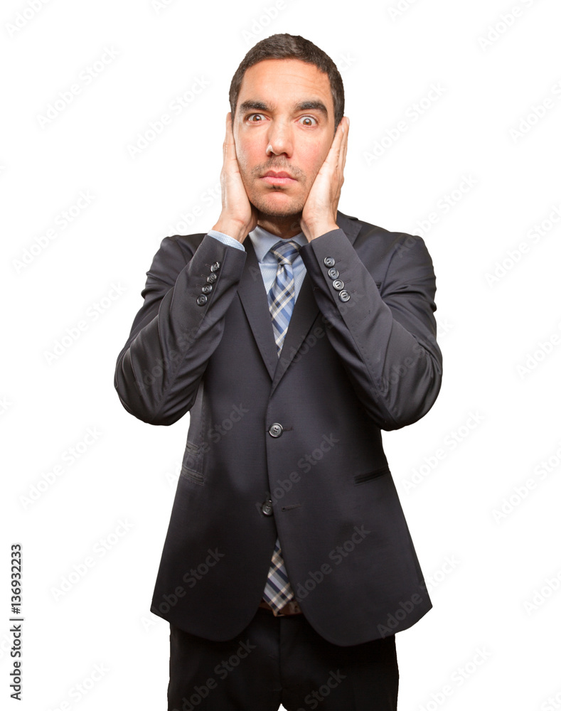 Worried young businessman covering his ears Worried young businessman covering his ears