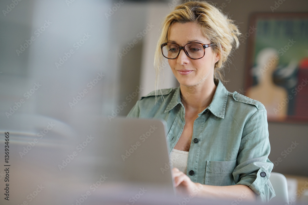 Portrait of blond woman working from home on laptop computer - obrazy, fototapety, plakaty 