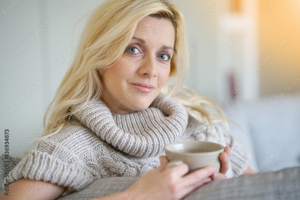 Middle-aged blond woman drinking tea in sofa Middle-aged blond woman drinking tea in sofa