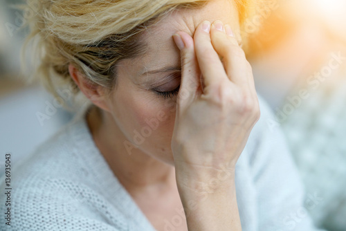 Portrait of middle-aged blond woman having a migraine photo