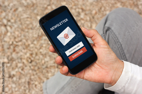Hand holding smart phone with subscribe newsletter concept on screen. All screen content is designed by me photo