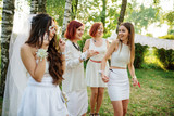 Girls wearing on white dresses having fun on hen party.