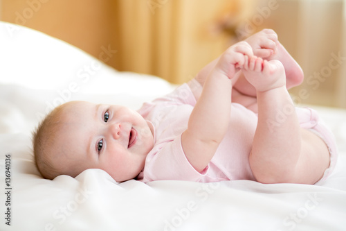 Funny chubby baby infant girl playing with her feet