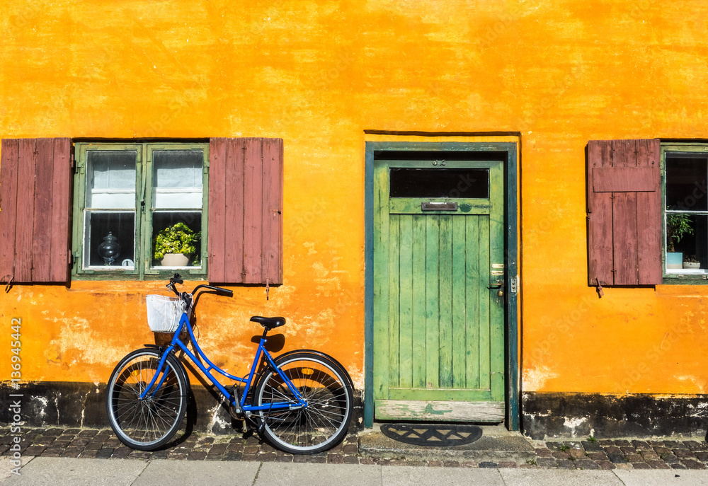 Blue Bike on Yellow Wall Next to Green Door