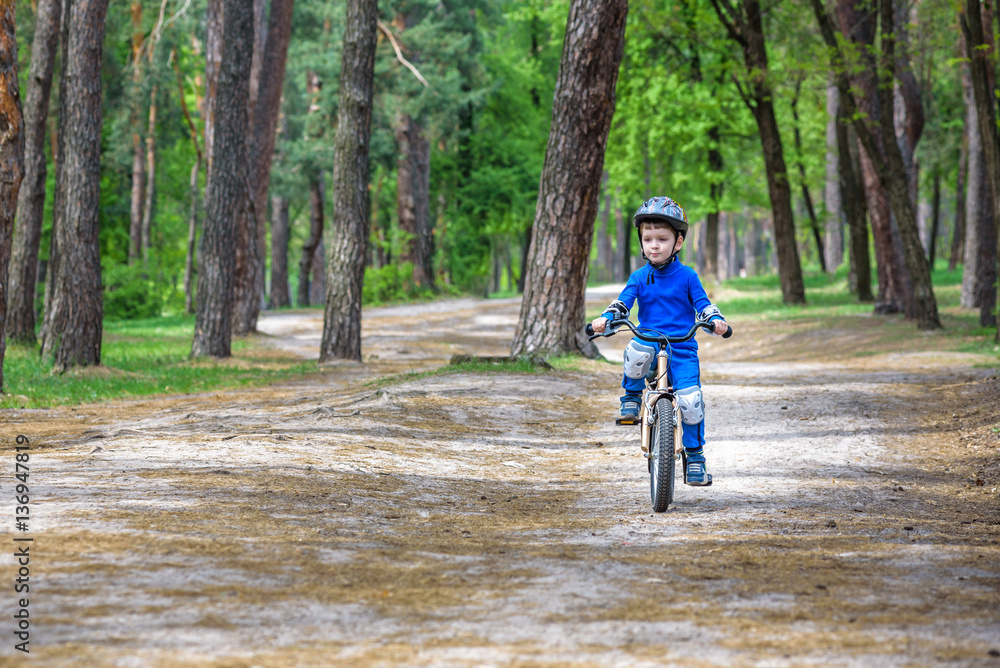 Happy cute blond kid boy having fun his first bike on sunny summer day, outdoors. child making sports. Active leisure for children. wear safety helmet. is smiling and cicling. Happy cute blond kid boy having fun his first bike on sunny summer day, outdoors. child making sports. Active leisure for children. wear safety helmet. is smiling and cicling.