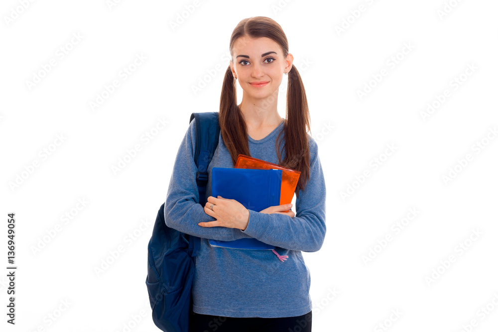 young attractive brunette student woman with blue backpack on her shoulder and folder for notebooks in hands looking at the camera isolated on white background young attractive brunette student woman with blue backpack on her shoulder and folder for notebooks in hands looking at the camera isolated on white background