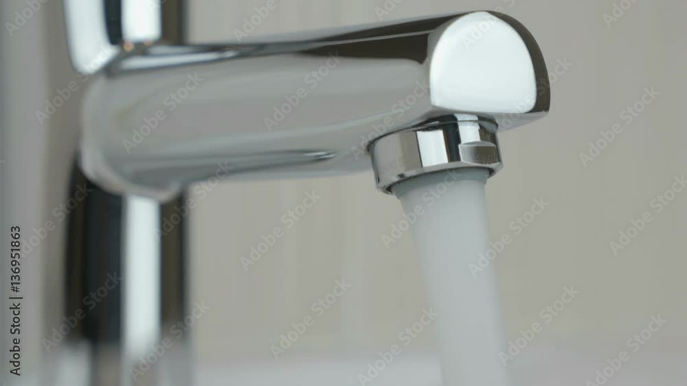 Strong stream of water flows from chrome-plated faucet into sink. Close-up Strong stream of water flows from chrome-plated faucet into sink. Close-up