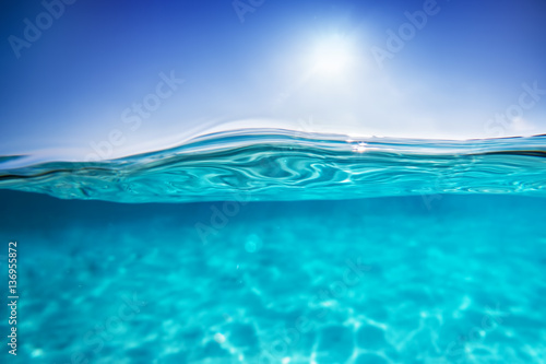 Fototapeta Naklejka Na Ścianę i Meble -  Half underwater shot, clear water and sunny blue sky. Tropical ocean