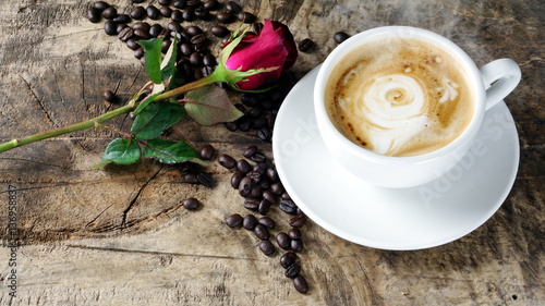 Cappuccino coffee with roses. A cup of latte, cappuccino or espresso coffee with milk put on a wood table with dark roasting coffee beans. Drawing the foam milk on top.