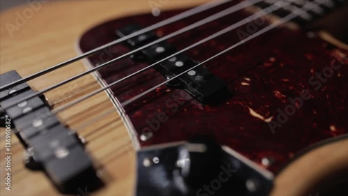 Vintage bass guitar in light wooden color. With red pickguard and two single pickups. Silver bridge. Close-up smooth motion.