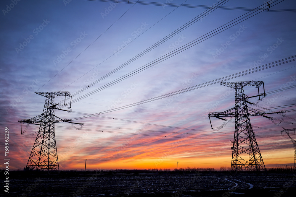 Fototapeta premium The silhouette of the evening electricity transmission pylon
