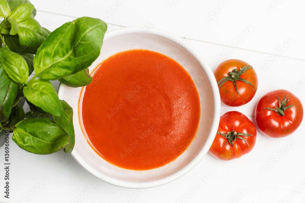 Sopa crema de tomate en cuenco blanco con albahaca sobre fondo blanco aislado. Vista superior Sopa crema de tomate en cuenco blanco con albahaca sobre fondo blanco aislado. Vista superior