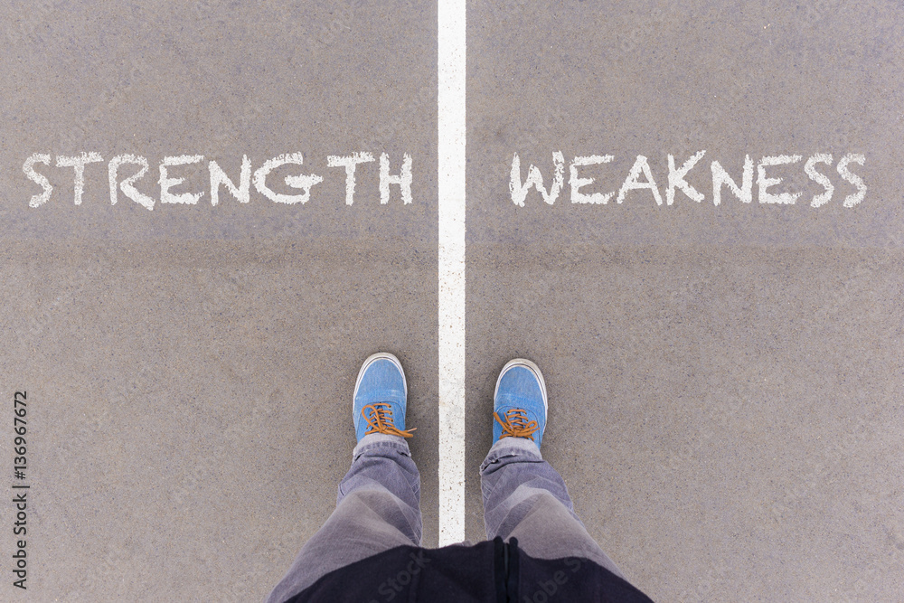 Strength and weakness text on asphalt ground, feet and shoes on