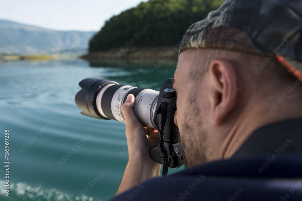 Obraz premium Photographer in nature taking pictures to a beautiful lake