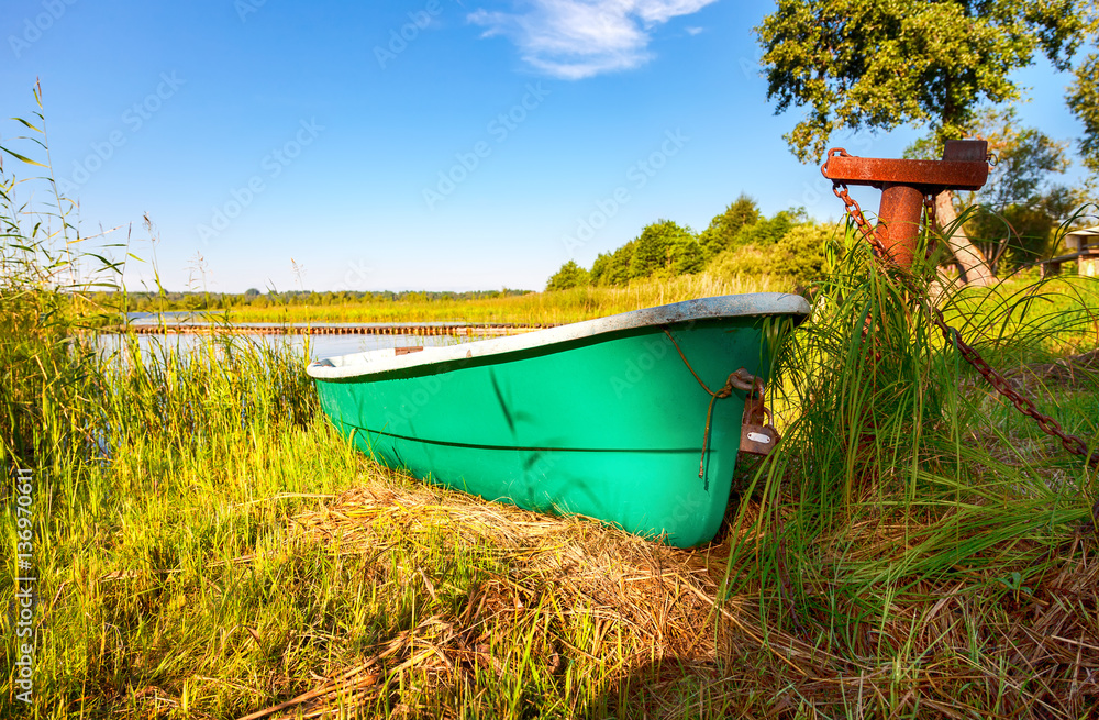Old green plastic fishing boat moored at the lake in summer sunn Old green plastic fishing boat moored at the lake in summer sunn