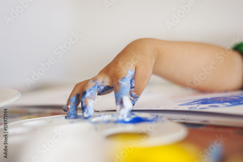 Toddler drawing with colored water color with fingers on a table