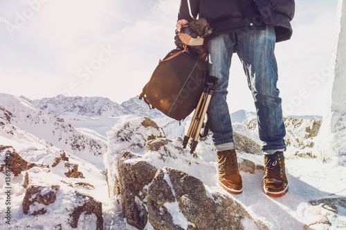 Photographer traveler on a mountain top with equipment in hands