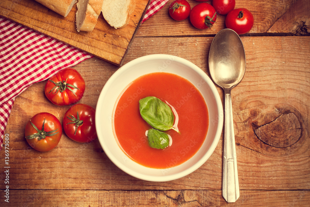 Sopa crema de tomate en cuenco blanco con albahaca sobre mesa de madera. Vista superior Sopa crema de tomate en cuenco blanco con albahaca sobre mesa de madera. Vista superior