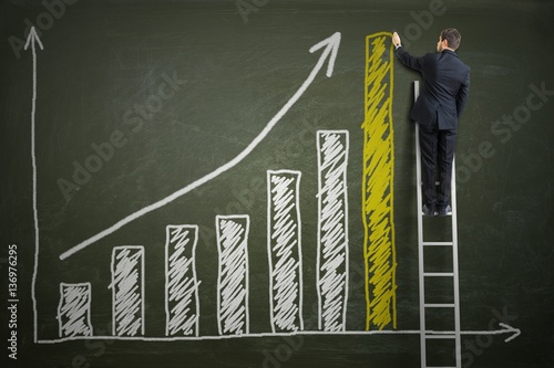 Successful businessman is standing on ladder and drawing growing graph of profit on blackboard. Investment concept.