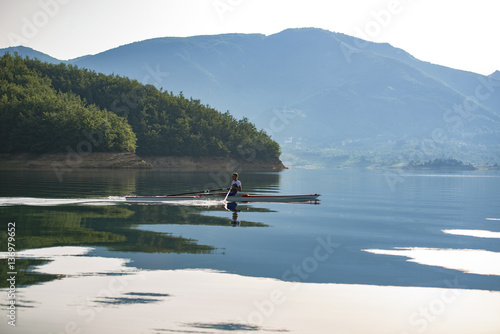 A Young single scull rowing competitor paddles on the tranquil lake © FS-Stock