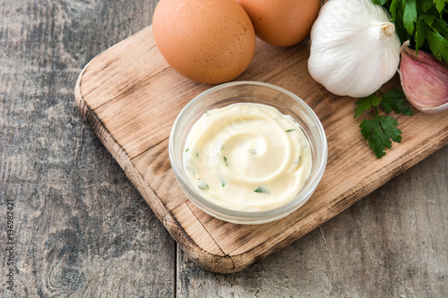 Aioli sauce and ingredients on wooden background
