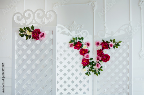 White delicate decorative wood panel in classical interior. Boudoir wedding room. Retro folding screen with flowers. Vintage ornate carved folding screen.