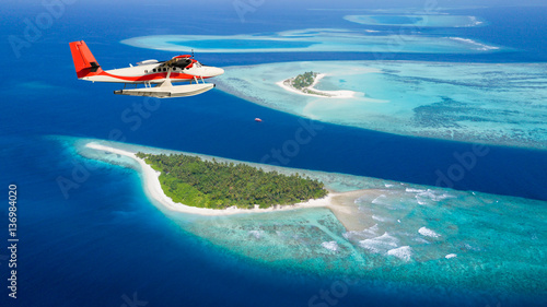 Sea plane flying above Maldives islands photo