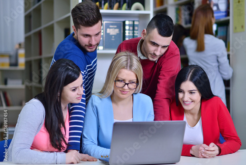 Group Of Students Working Together In Library With Teacher