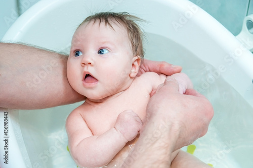Bathing baby in a baby bath.