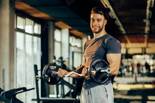 Handsome man doing biceps lifting in a gym