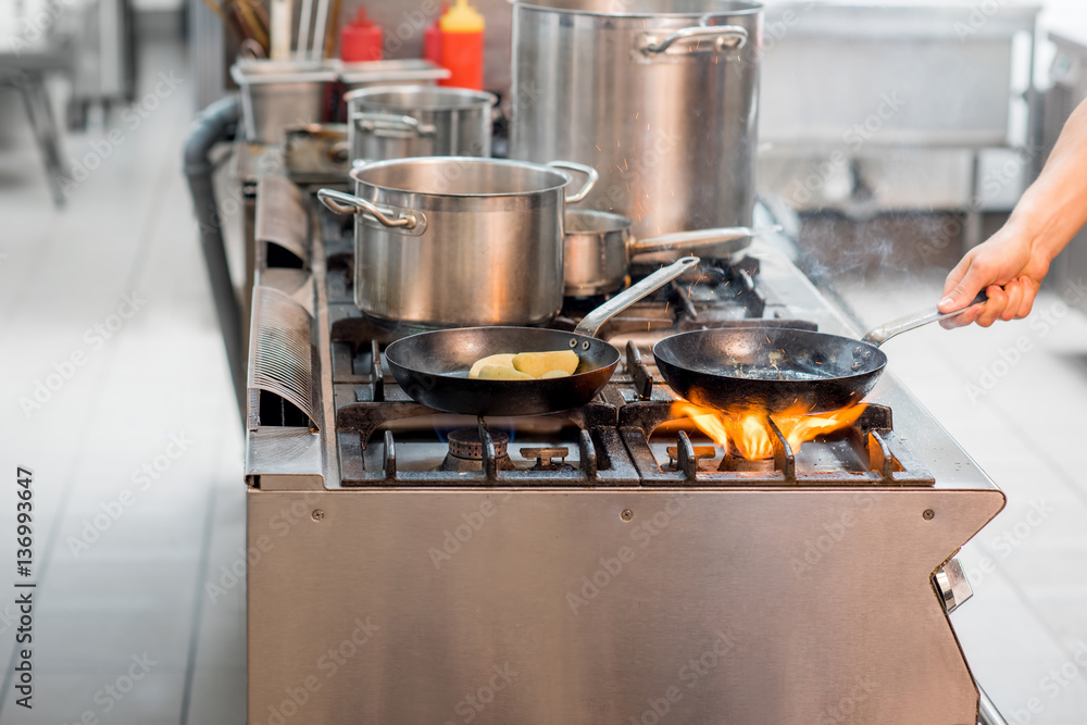 Chef frying meat steak on the gas stove with fire at the kitchen. Close-up view on the frying pan Chef frying meat steak on the gas stove with fire at the kitchen. Close-up view on the frying pan