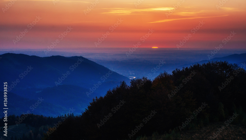 Red sunset in the mountains landscape with sunny beams. Carpathi