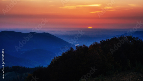 Red sunset in the mountains landscape with sunny beams. Carpathi