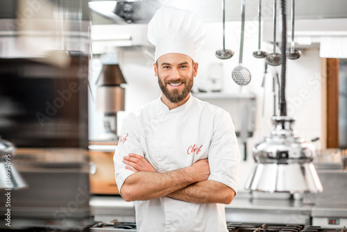 Portrait of handsome positive chef cook at the restaurant kitchen photo